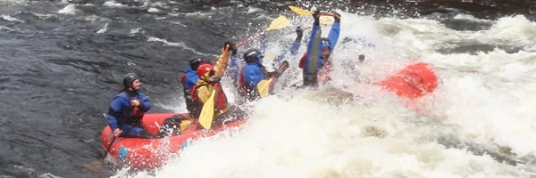 North Creek guides and guests paddle a red raft through Hudson River whitewater