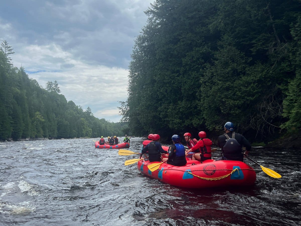 North Creek guides and guests paddle a red raft through Hudson River whitewater