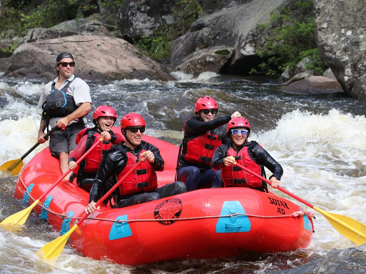 North Creek guides and guests paddle a red raft through Hudson River whitewater